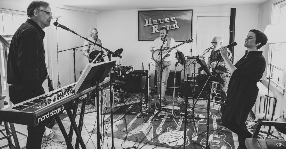 Group of people in room with various instruments playing and woman singing into microphone at SKYBOKX 109 Sports Bar & Grill in Natick, MA